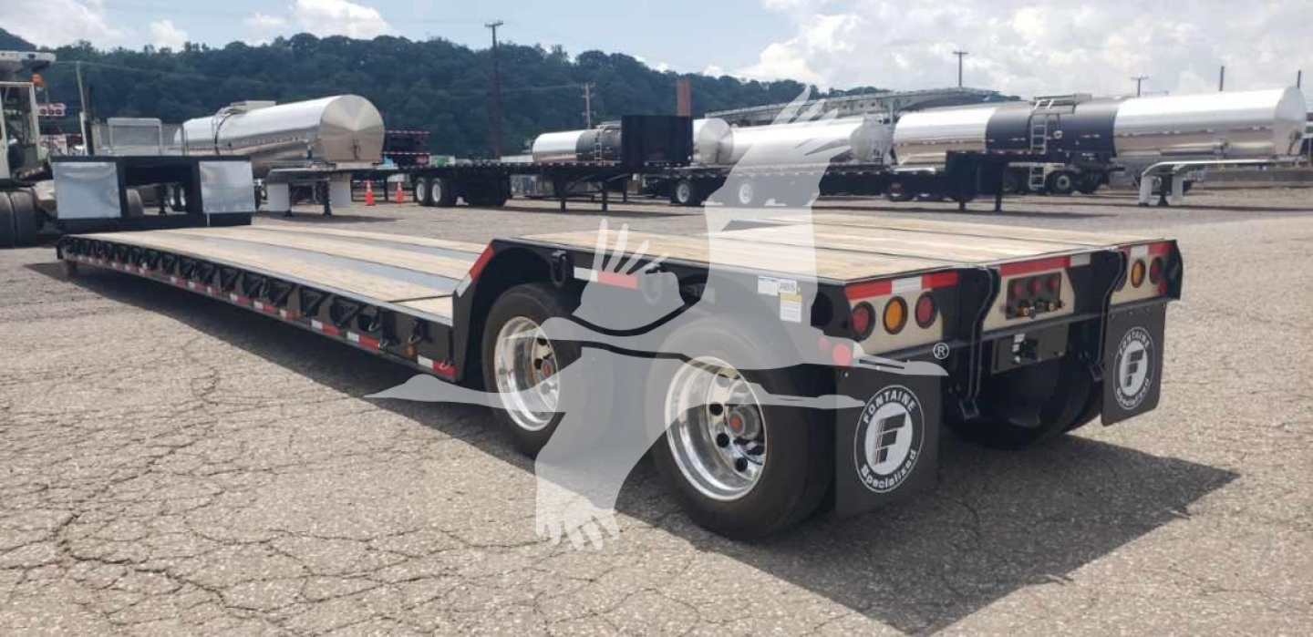 Fontaine Renegade X20 trailer with black metal frame and multiple axles, rear view showing tandem wheels and tail lights; some white cylindrical tanks in background.