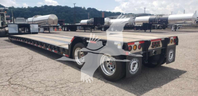 Fontaine Renegade X20 trailer with black metal frame and multiple axles, rear view showing tandem wheels and tail lights; some white cylindrical tanks in background.