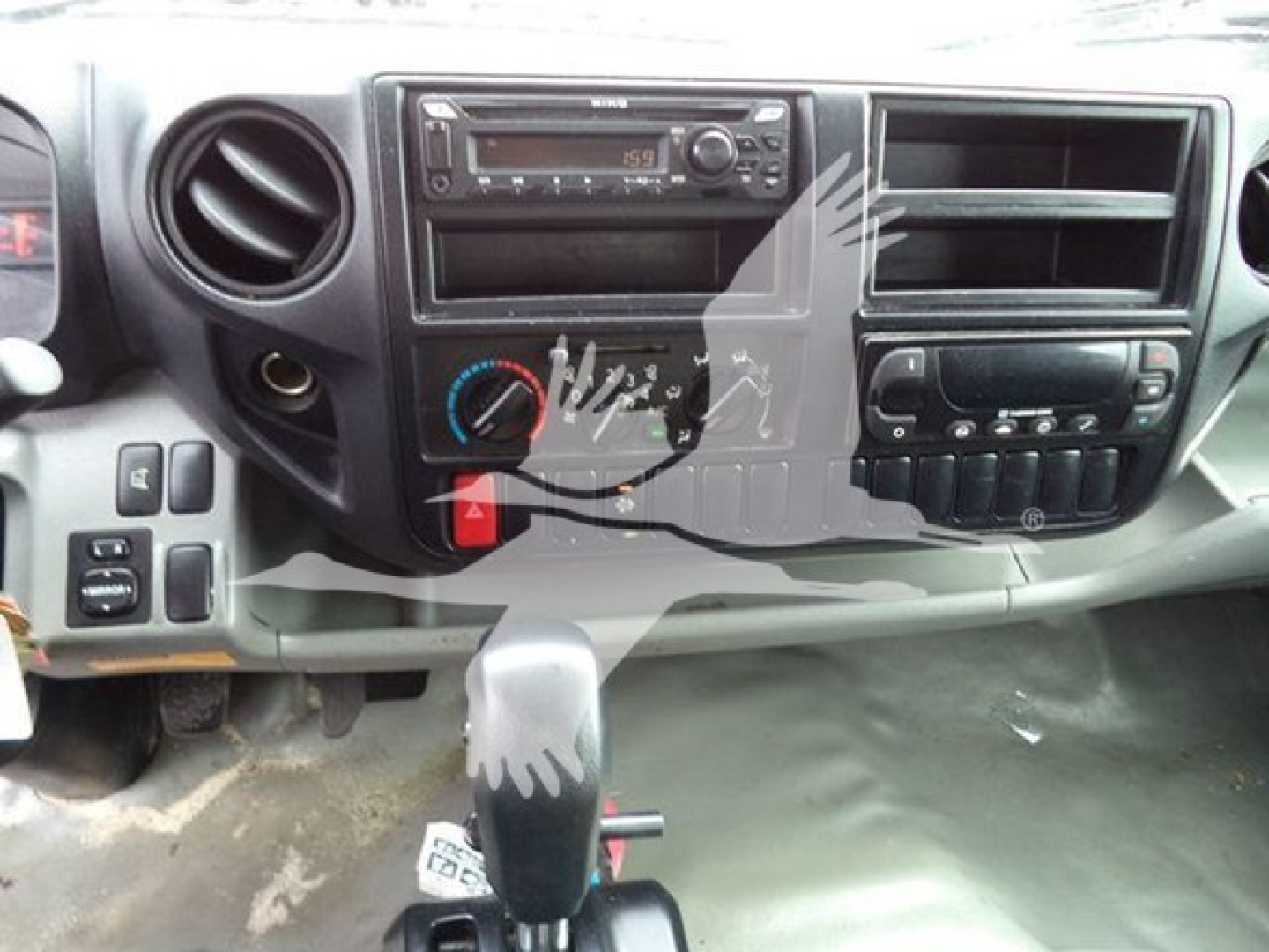 Dashboard of a 2019 Hino 195 refrigerated truck showing factory radio, HVAC controls, steering column area, and gear selector with some wear.