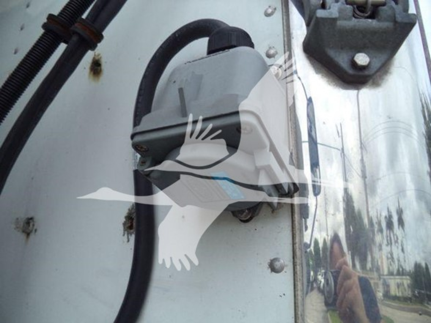 Hino refrigeration truck door area showing a gray electrical component mounted on a white panel with black wiring harness and bolts.