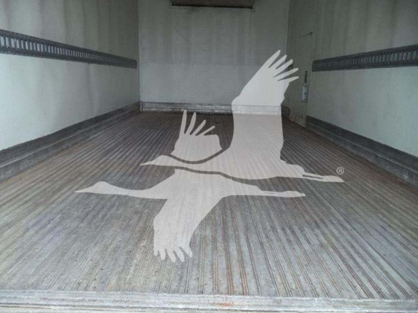 Truck cargo area showing wooden floor of a refrigerated box interior with ridged metal walls.