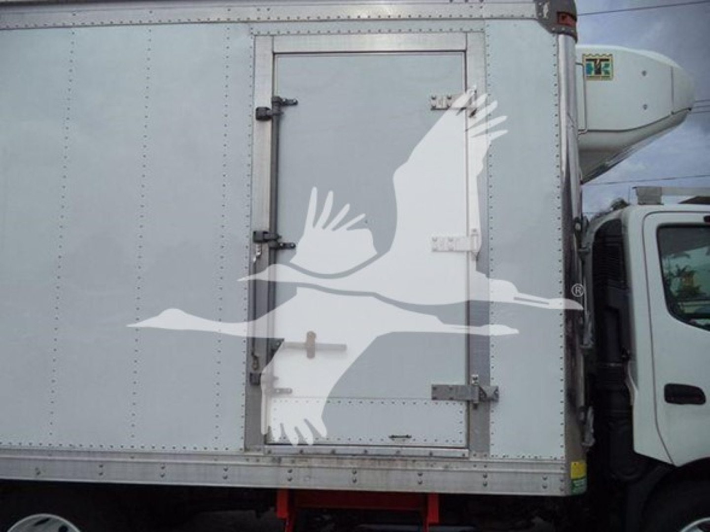 Rear door of a 2019 Hino 195 refrigerated truck cargo box with exterior paneling and side view mirror visible.
