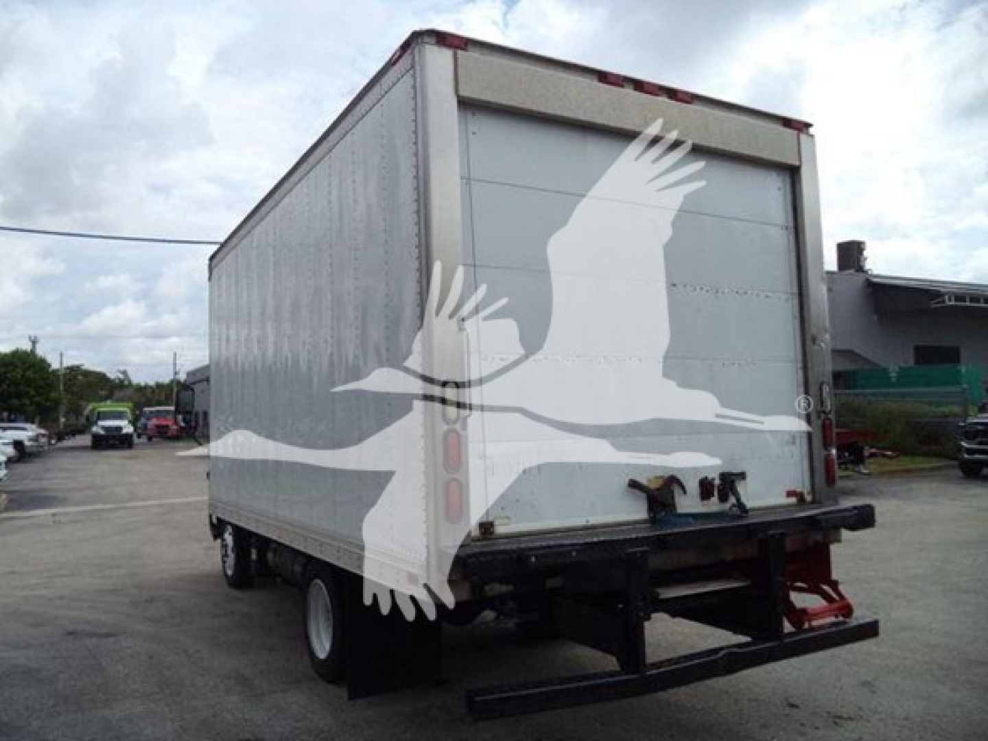 Truck rear view showing white enclosed refrigerated box on chassis with lift gate and taillights.