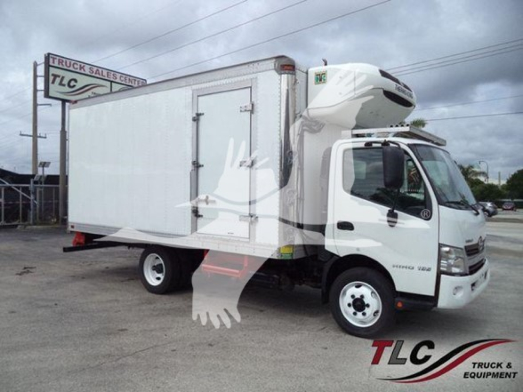 Truck side view of a 2019 Hino 195 refrigerated box truck with a white cab and cargo box; visible branding includes TLC Truck Sales Center sign, and a refrigeration unit on the cab roof.