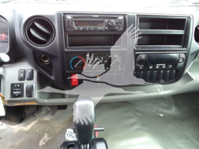 Dashboard of a 2019 Hino 195 refrigerated truck showing factory radio, HVAC controls, steering column area, and gear selector with some wear.