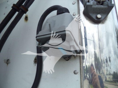 Hino refrigeration truck door area showing a gray electrical component mounted on a white panel with black wiring harness and bolts.