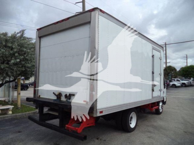Box truck with white refrigerated body and black underride bumper, rear view showing red suspension components and dual rear wheels.