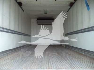 Interior of a refrigerated truck cargo area with ribbed metal floor and an overhead unit, empty cargo space.