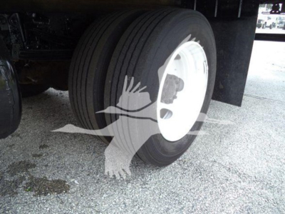 Front dual tires visible with white wheel rims under a refrigerated truck; no legible manufacturer text on tire sidewall.
