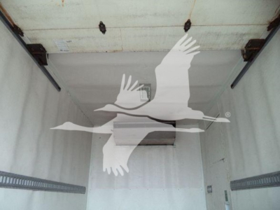 Trailer truck interior showing empty refrigerated cargo area with white walls and a small refrigeration unit mounted on the ceiling.