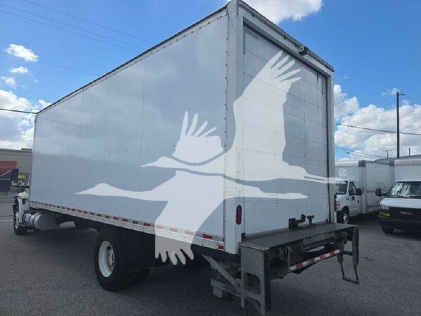 Rear/side view of a box truck showing a large cargo box and a hydraulic lift at the rear.