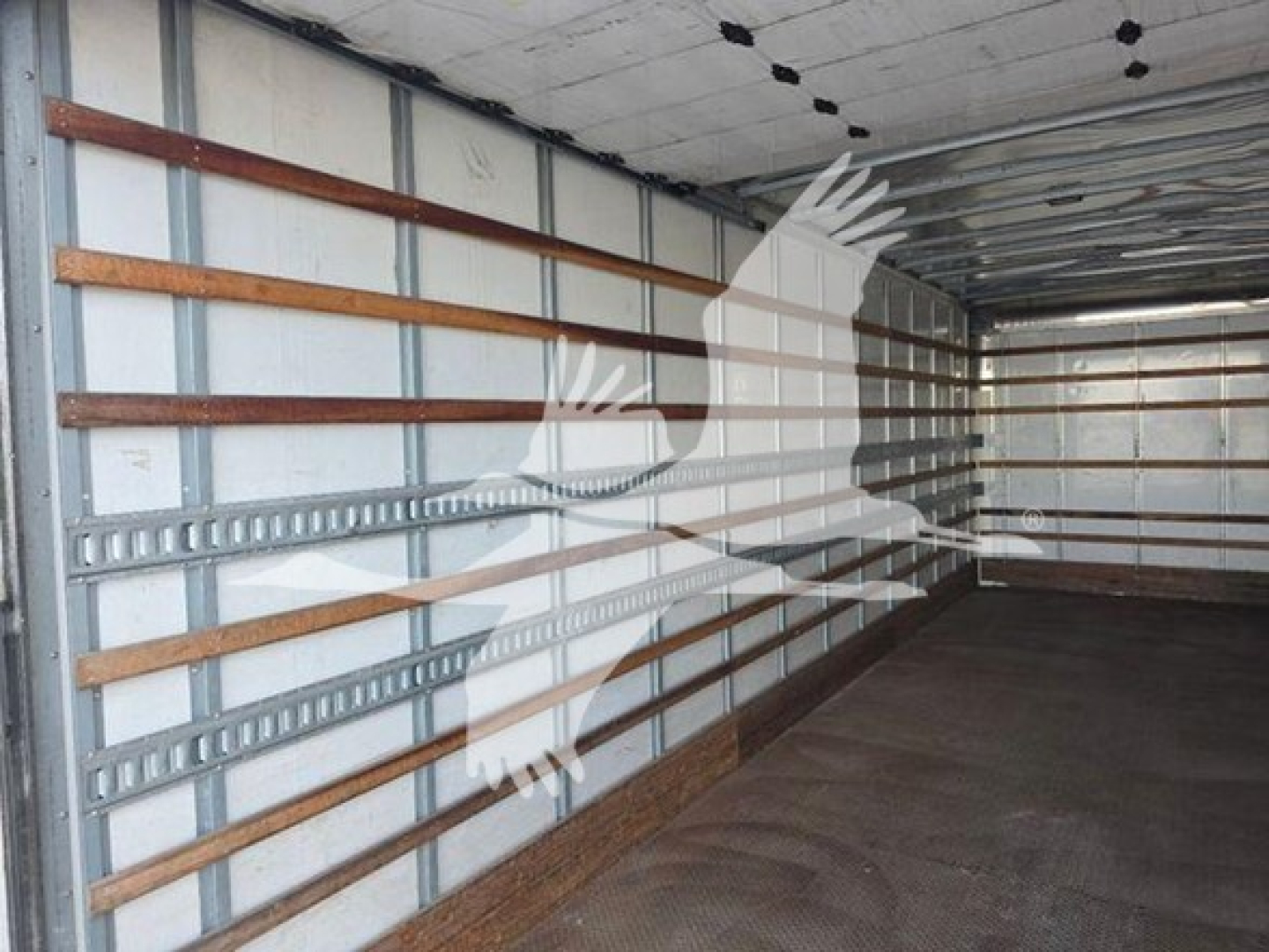 Interior of a white cargo box truck showing metal wall rails and wooden side planks along the right wall.