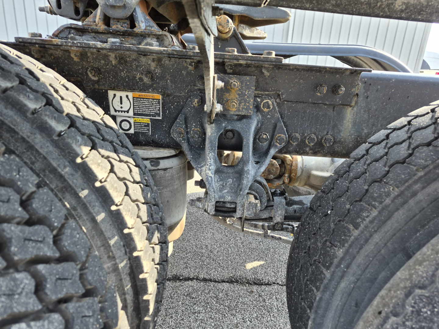 Kenworth T880 chassis view showing front suspension and tires with warning sticker and hydraulic lines, undercarriage detail visible.