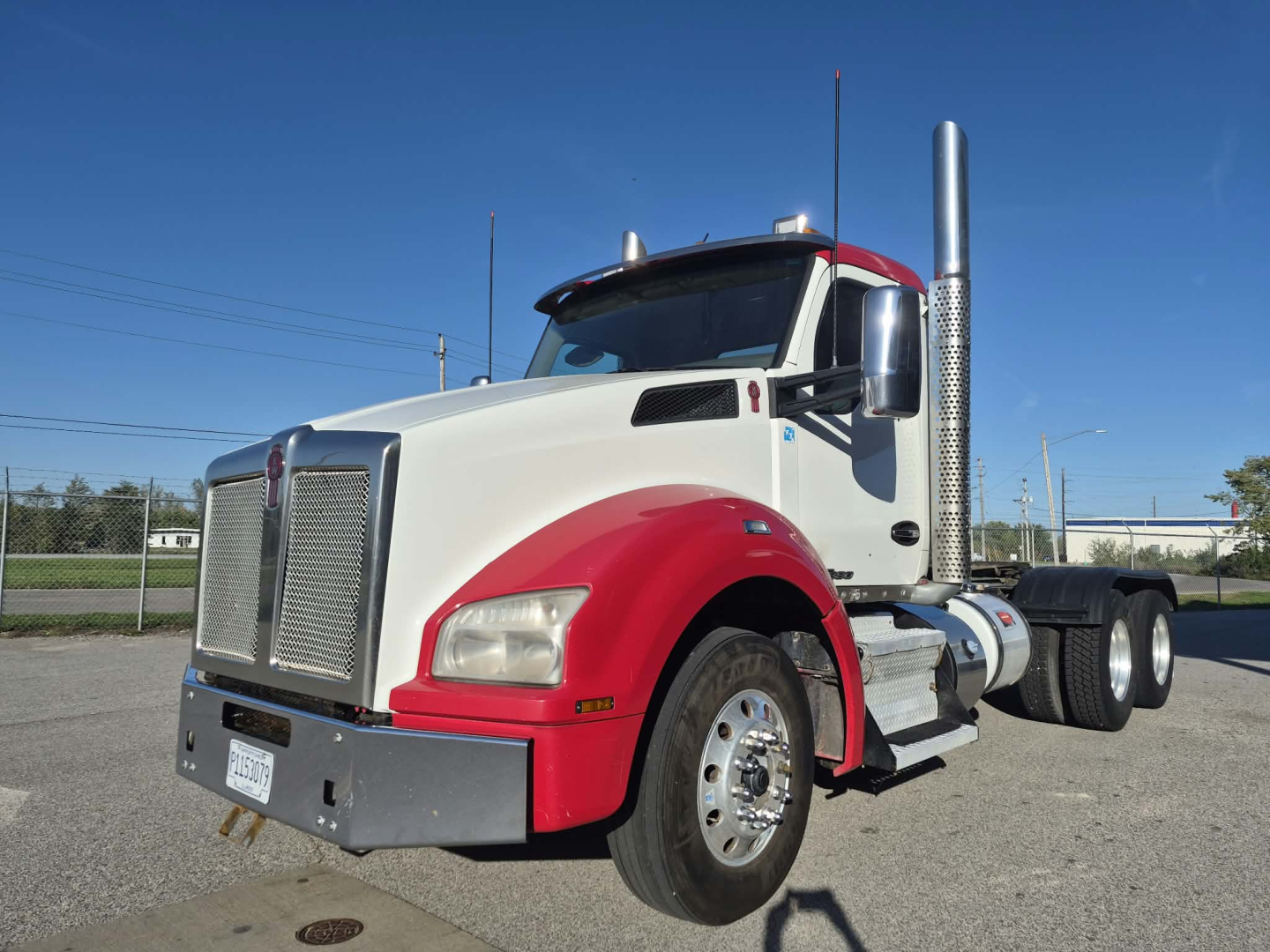 Kenworth T880 conventional daycab truck in white with red fenders, chrome exhaust stack, front chrome bumper, side steps, and dual rear axles.