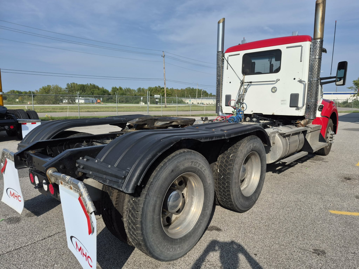 Kenworth T880 conventional daycab tractor rear view showing triple axle drivetrain and fifth wheel connection.