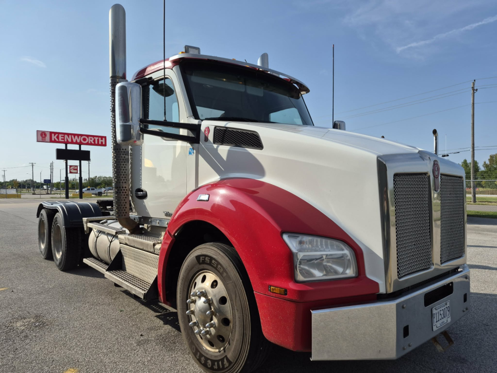 Kenworth T880 conventional daycab truck with white cab and red fenders, large chrome grille, dual exhaust stacks, front bumper and wheel details visible.