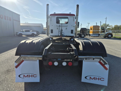 Kenworth T880 rear view showing fifth wheel, dual rear axles, dual exhaust stacks, mud flaps with MHC logo, and rear bumper lights.