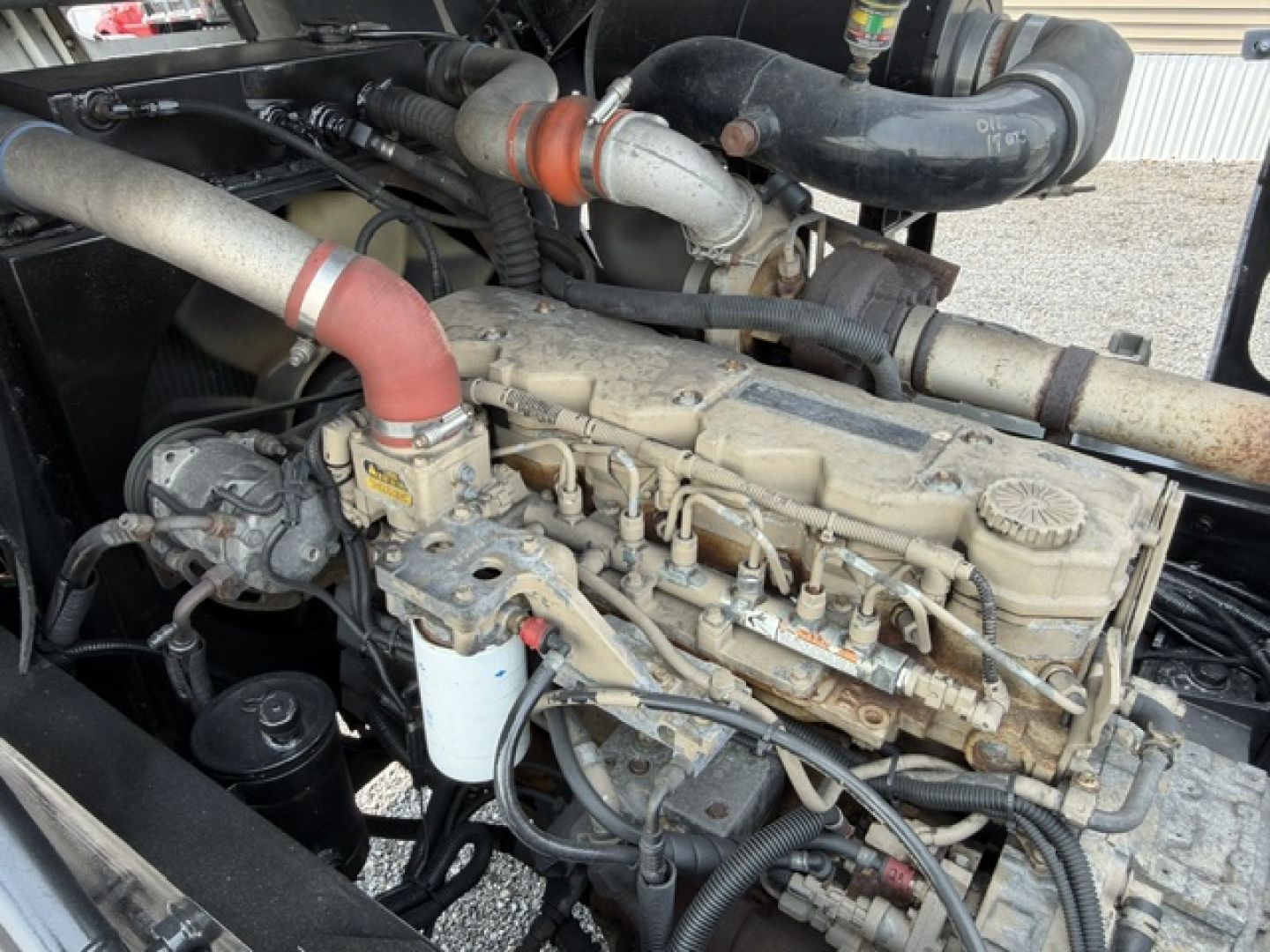 Capacity TJ5000 engine bay showing diesel engine with intake hoses, red coolant hose, oil filter, and fuel line hardware.