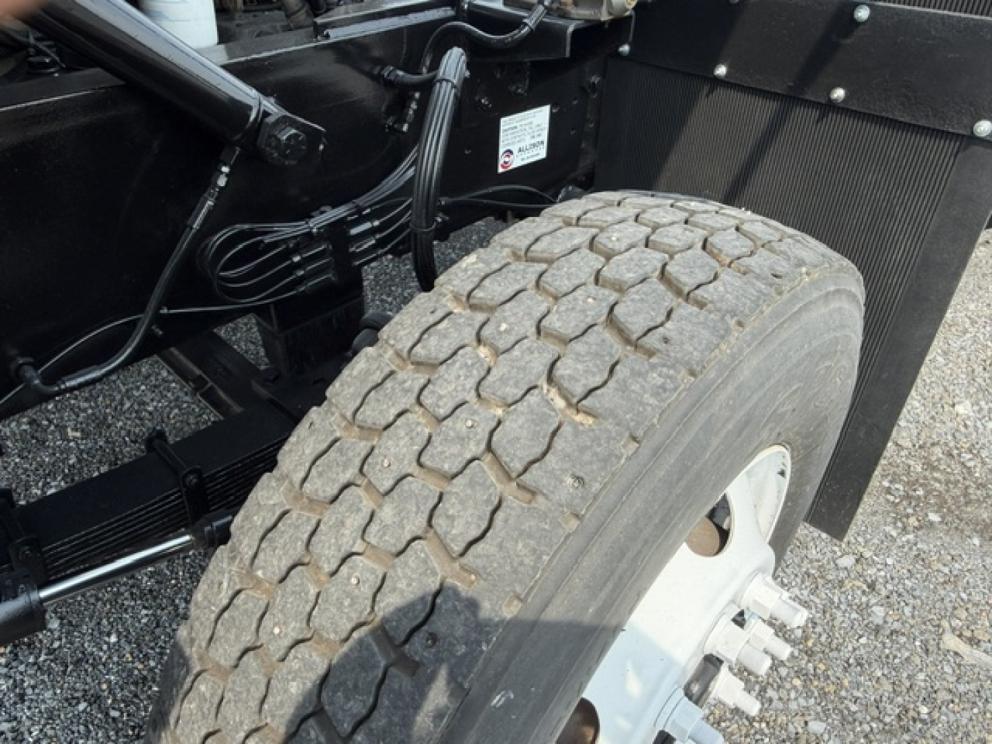 Truck chassis and front wheel showing TJ5000 capacity with heavy tread tire, suspension, and frame components visible.