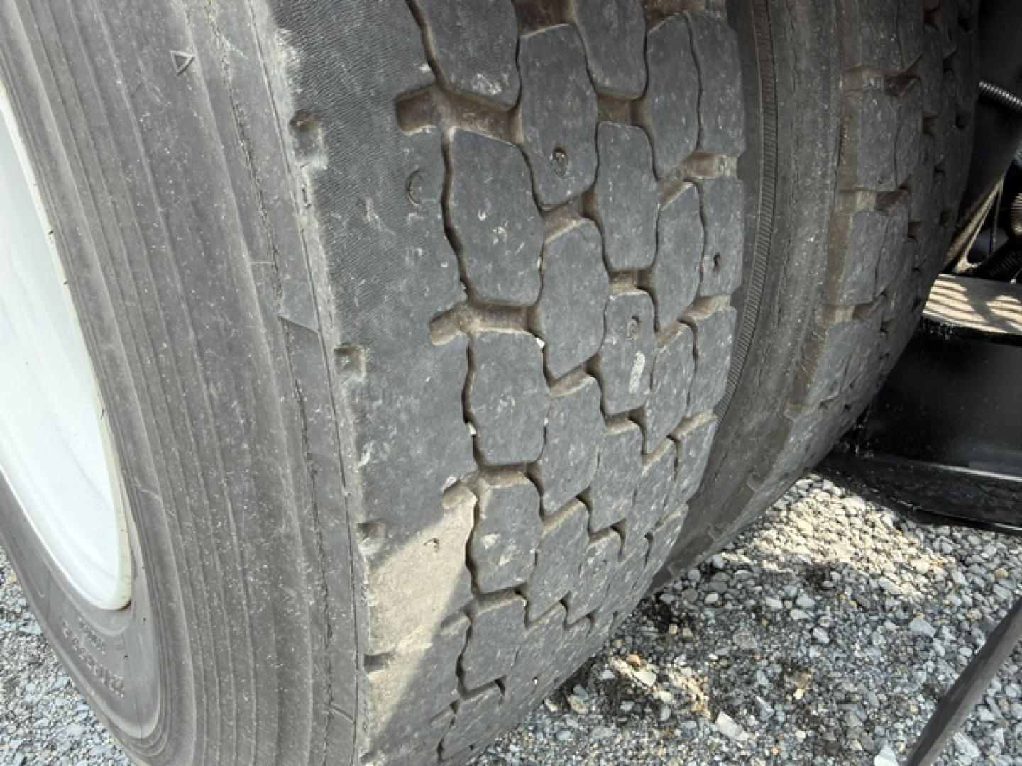 Tandem axle truck tires with tread pattern and gravel surface visible in foreground.
