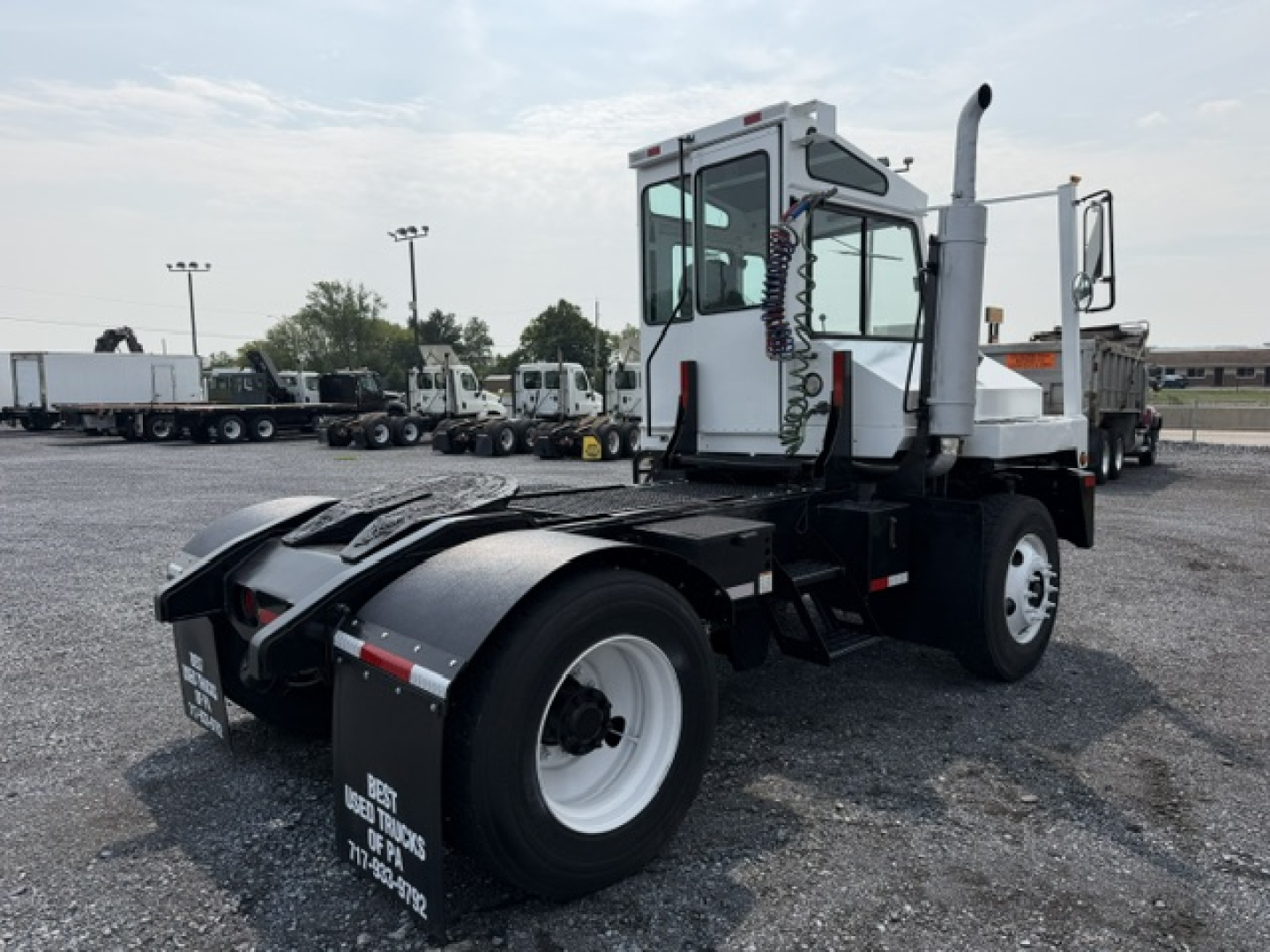 Truck chassis with TJ5000 capacity, rear view showing fifth wheel hitch and enclosed cab, white wheels, on gravel lot.