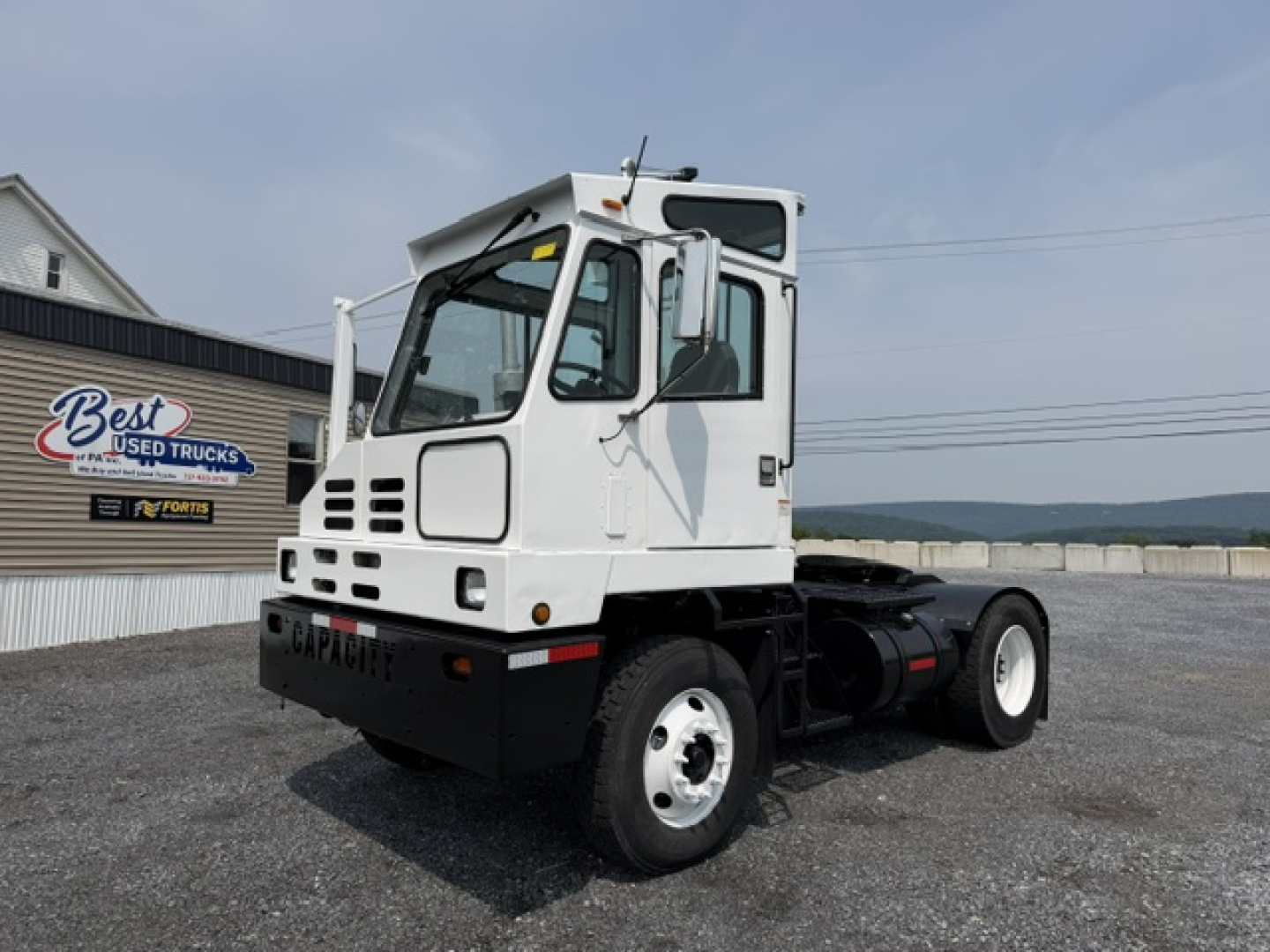 Capacity TJ5000 yard truck in side view showing white cab and chassis with black bumper and twin rear wheels.