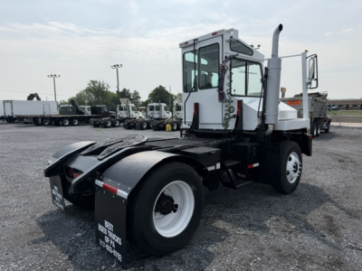 Truck chassis with TJ5000 capacity, rear view showing fifth wheel hitch and enclosed cab, white wheels, on gravel lot.