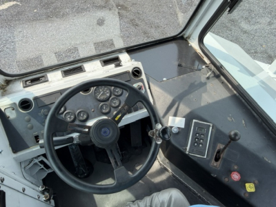Truck cab interior with steering wheel, dashboard gauges, and control panel. Visible text includes no legible labels beyond generic switches and gauges; no clear model or part numbers readable.