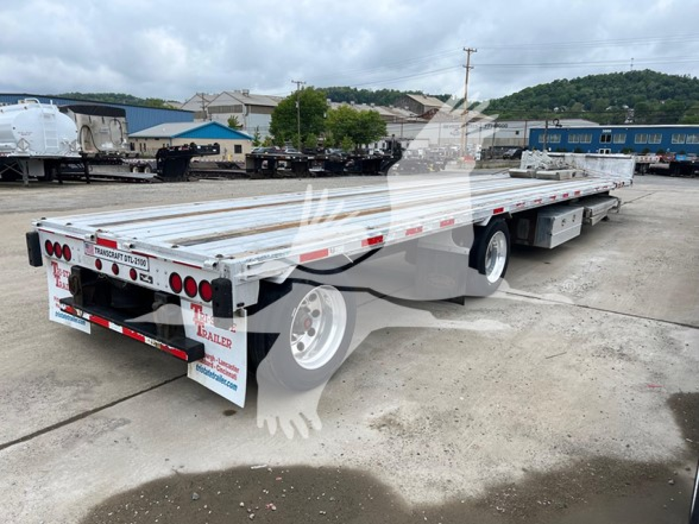 Trailer side view of 2014 Transcraft D-Eagle II drop deck trailer showing aluminum deck, dual rear axles, and taillight assemblies.