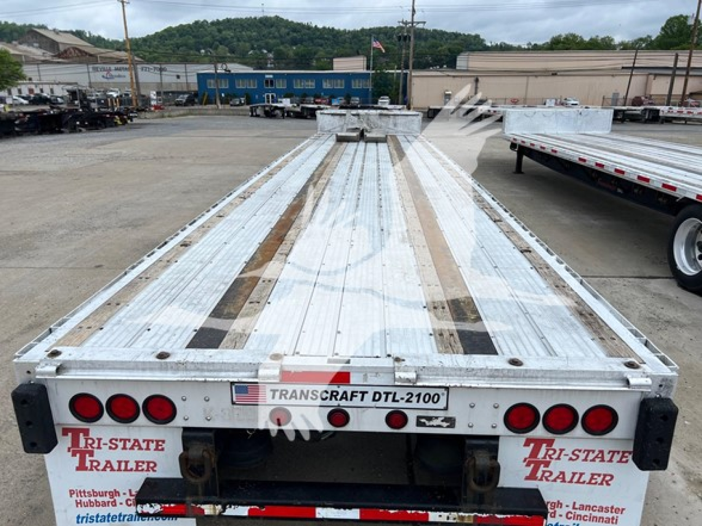 Transcraft D-Eagle II trailer bed showing rear with lights and deck; 'TRANSCRAFT DTL-2100' plate, Tri-State Trailer branding, silver aluminum deck with brown strips.