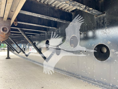 Trailer undercarriage showing Crossbeam and underside of drop deck with holes and support brackets.