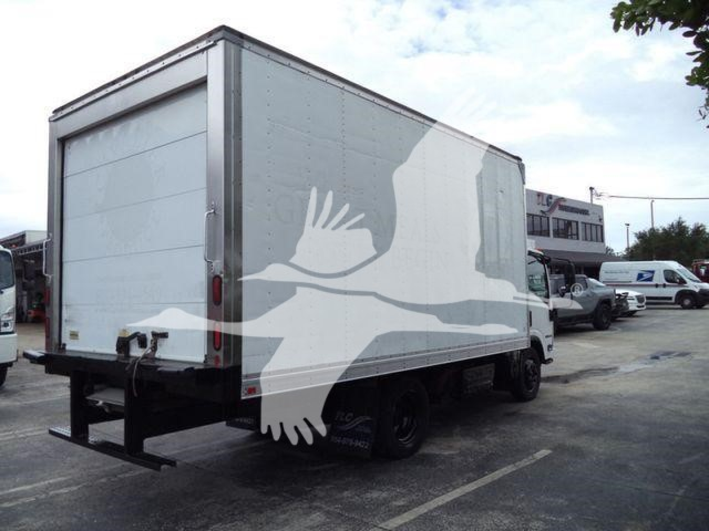 Isuzu NQR refrigerated truck box rear and side view with stock lot in background.
