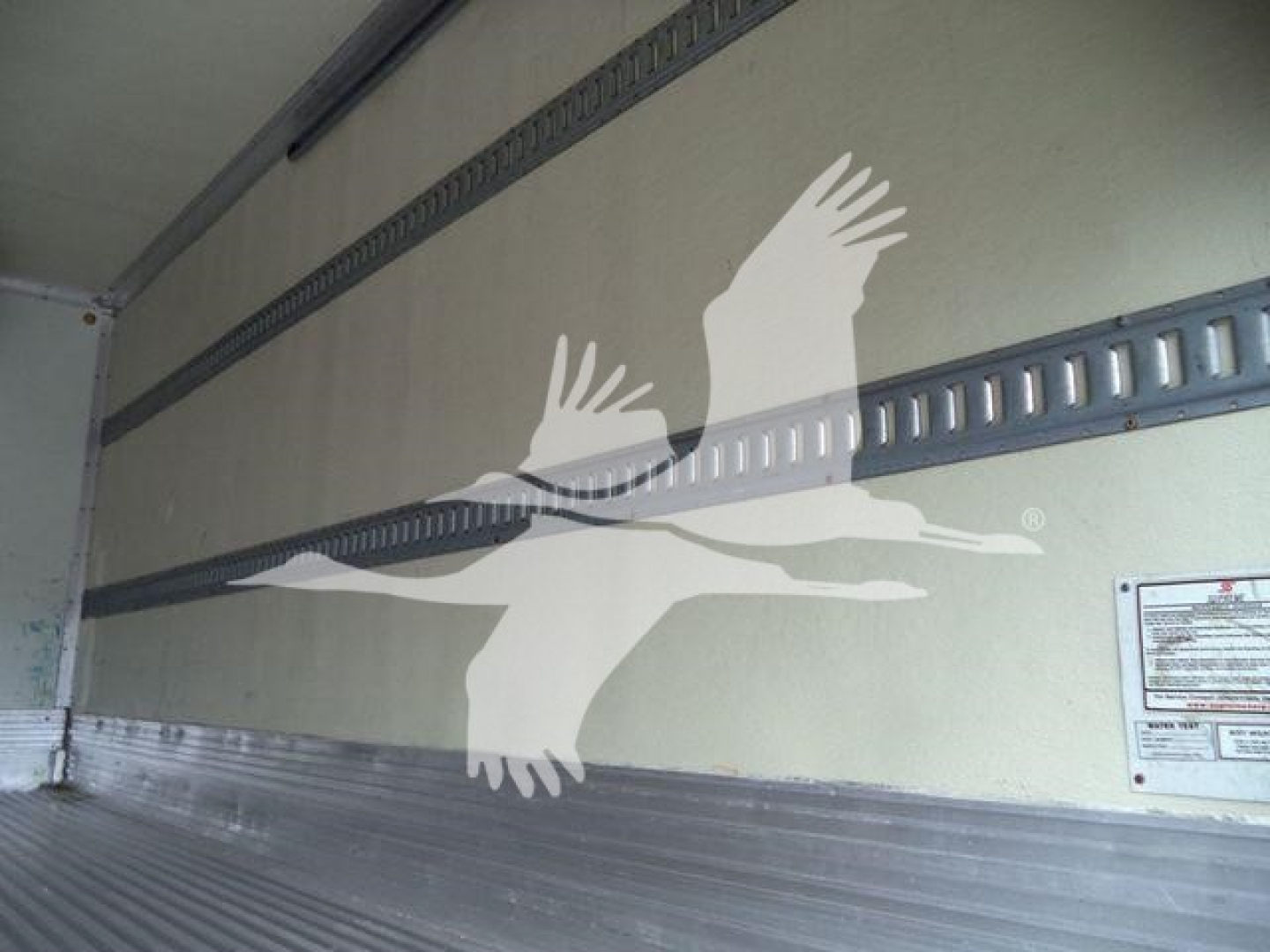 Isuzu NQR refrigerated truck interior wall with birds graphic and cargo area metal rails visible.