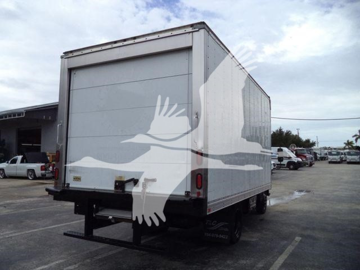 Isuzu NQR refrigerated box truck rear view showing back doors and platform hitch with white bird decal on side.