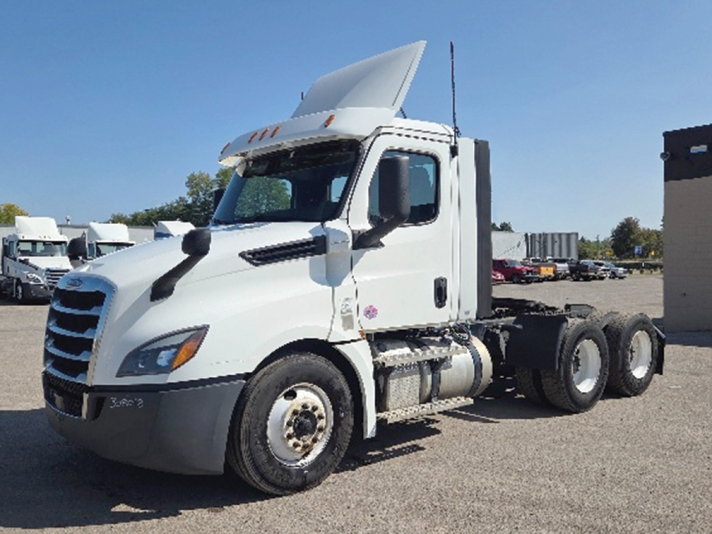 Freightliner Cascadia126 sleeperless day cab semi truck in white, side view showing cab, fuel tanks, and rear wheel axle.