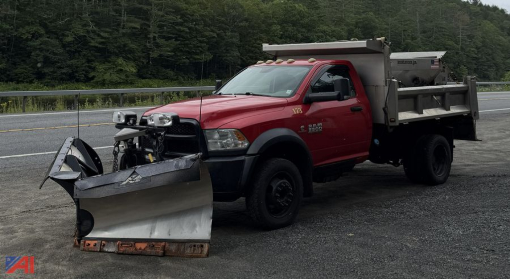 Ram 5500 dump truck with plow and sander attached; red cab, black wheels, front mounted snow plow, dump bed with side rails. Visible text on door: RAM 5500, 4x4.