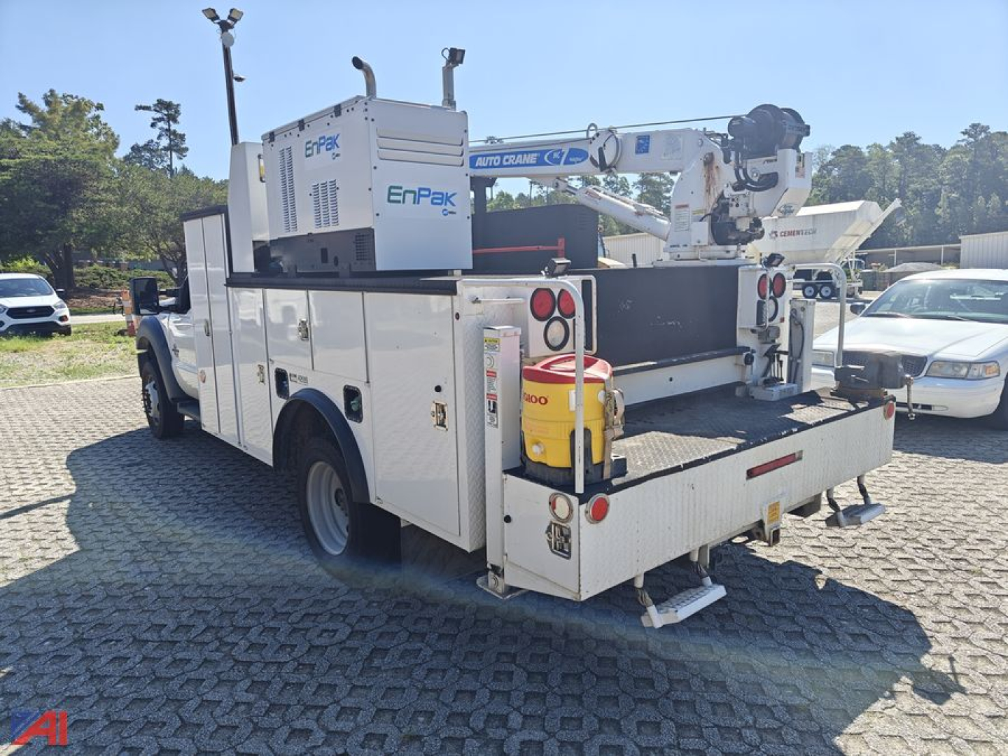 Ford F-550 Super Duty crane truck with mounted aerial boom and toolbox, rear view showing crane and hydraulic controls.