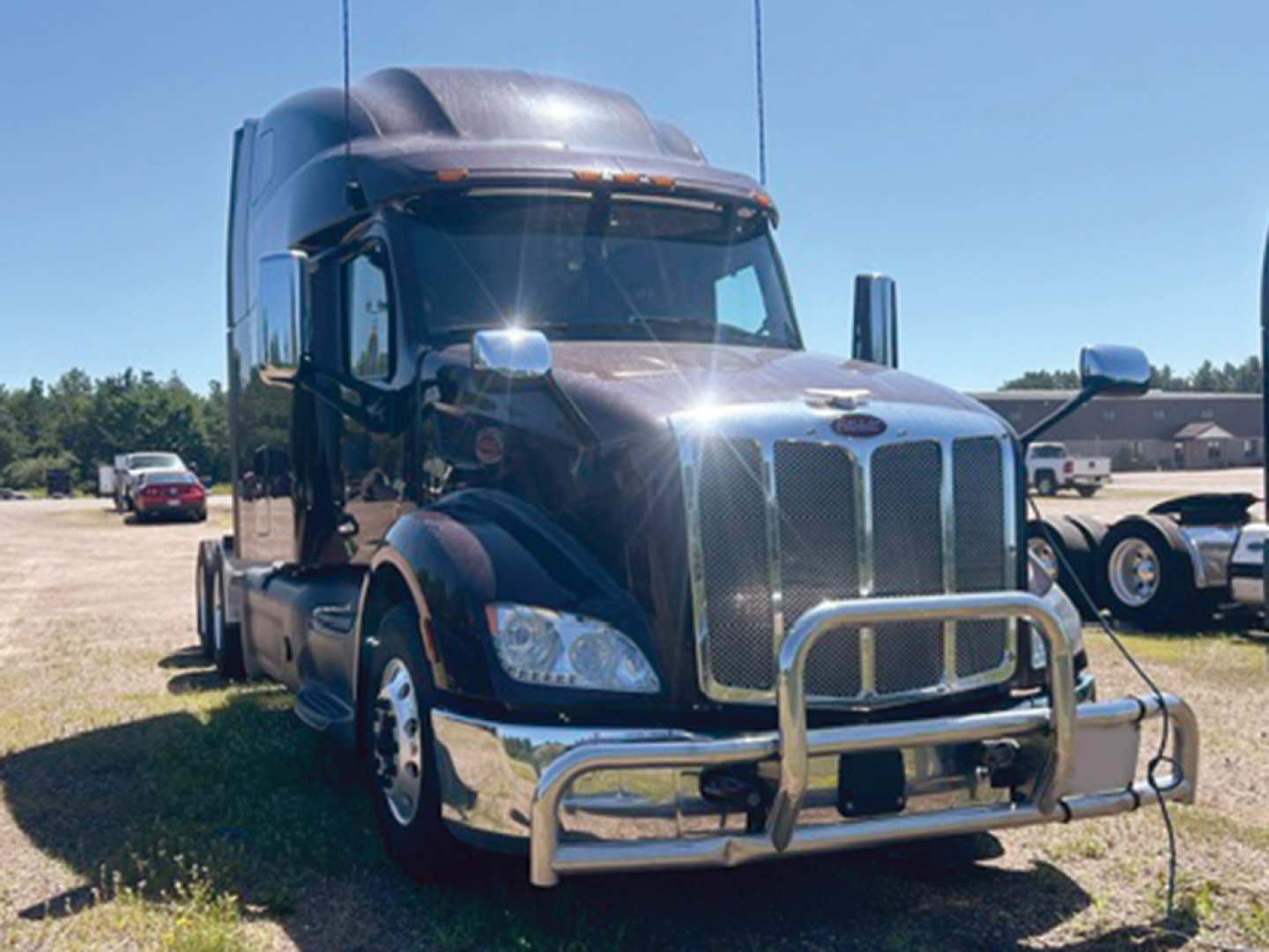 Peterbilt 579 truck front view with chrome grille guard and bumper, black cab, chrome mirrors, daytime outdoors.