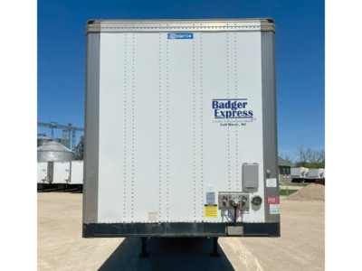 Trailer rear view showing Stoughton brand and Badger Express logo; vertical riveted panel doors, rear electrical box, and hitch area visible.