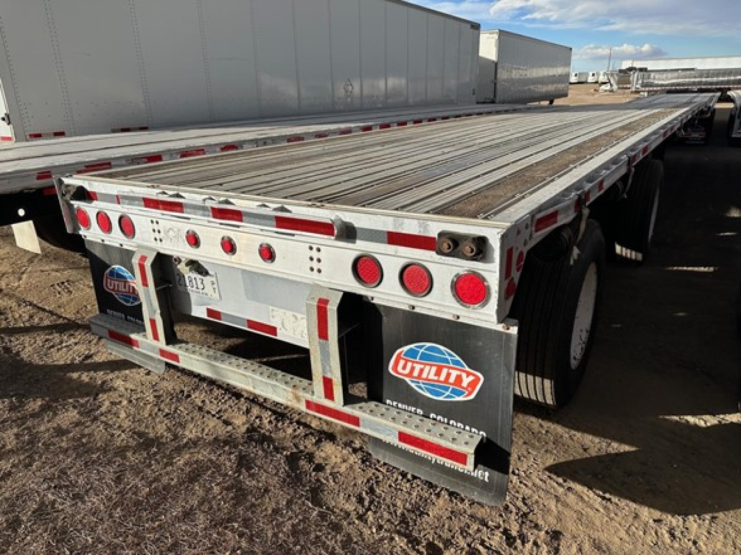 Flatbed trailer showing rear with Utility brand mud flaps and reflective tape.