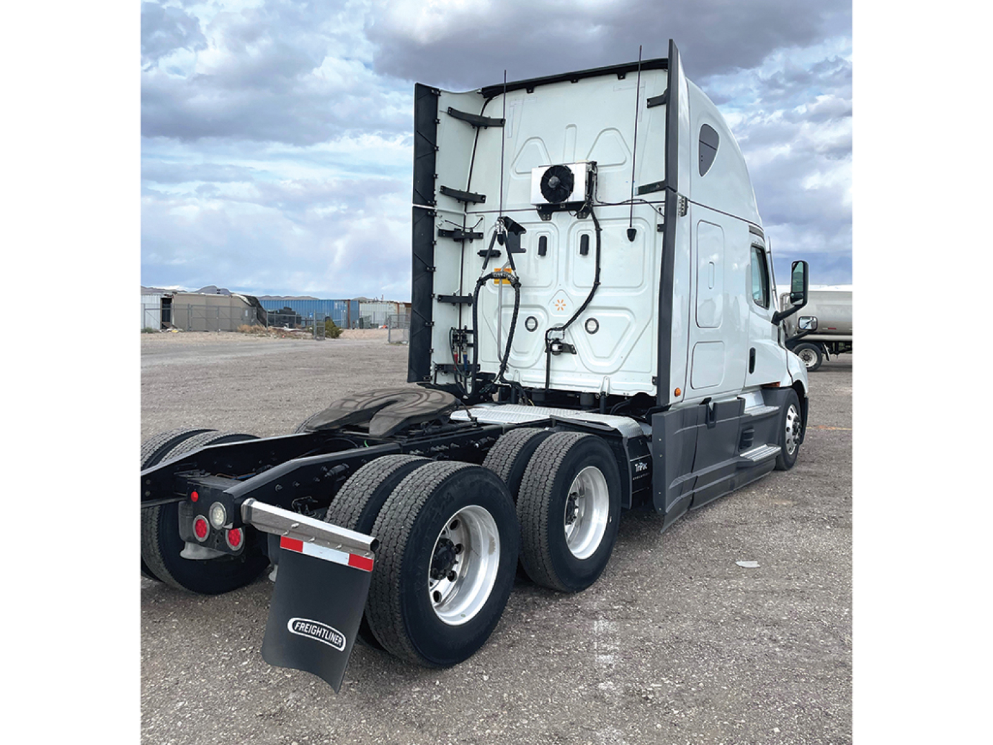 Truck rear view showing tandem axles and fifth wheel on a 2020 Freightliner Cascadia126 sleeper cab, with white cab and black chassis.