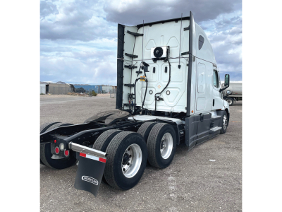 Truck rear view showing tandem axles and fifth wheel on a 2020 Freightliner Cascadia126 sleeper cab, with white cab and black chassis.