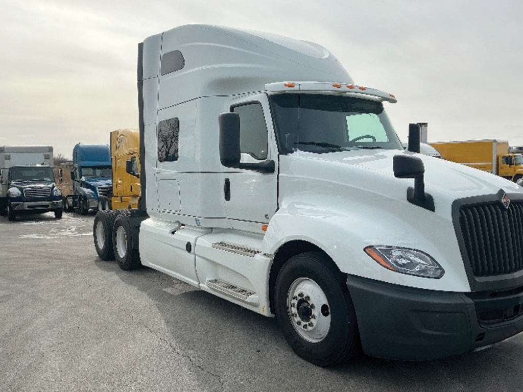 Truck cab of a 2020 International LT625 sleeper tractor, front right view, white with black bumper, showcasing the aerodynamic hood and side mirrors.