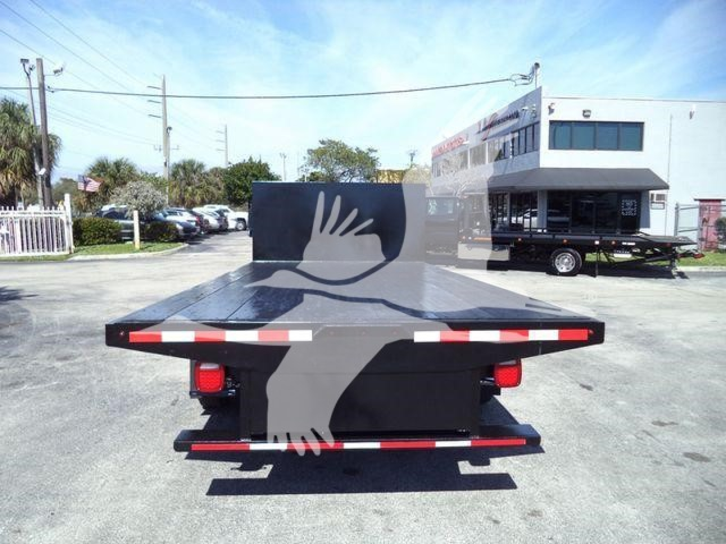 Rear view of a used 2011 Ford E450 flatbed truck showing a black flatbed and rear taillights.