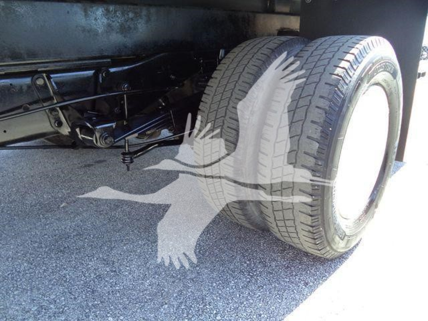 Ford E-450 chassis with dual rear wheels and trailer suspension visible underflatbed