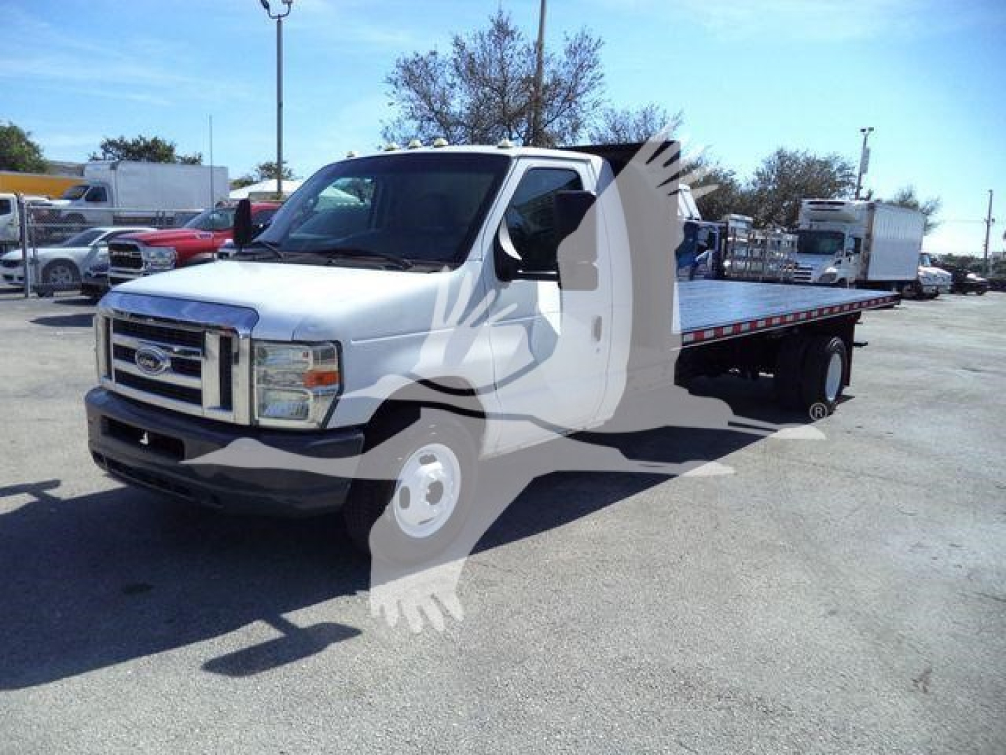 Ford E450 flatbed truck in a used inventory lot showing front and side view with flatbed cargo area.