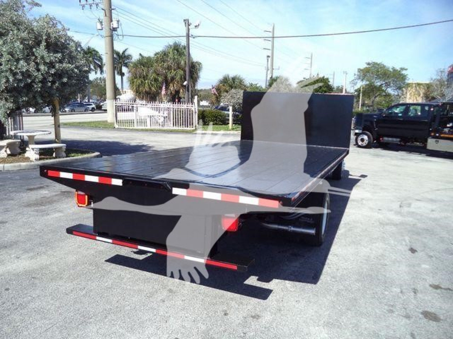 Flatbed truck rear view showing large aluminum deck and square headache rack on Ford E450 flatbed work truck.