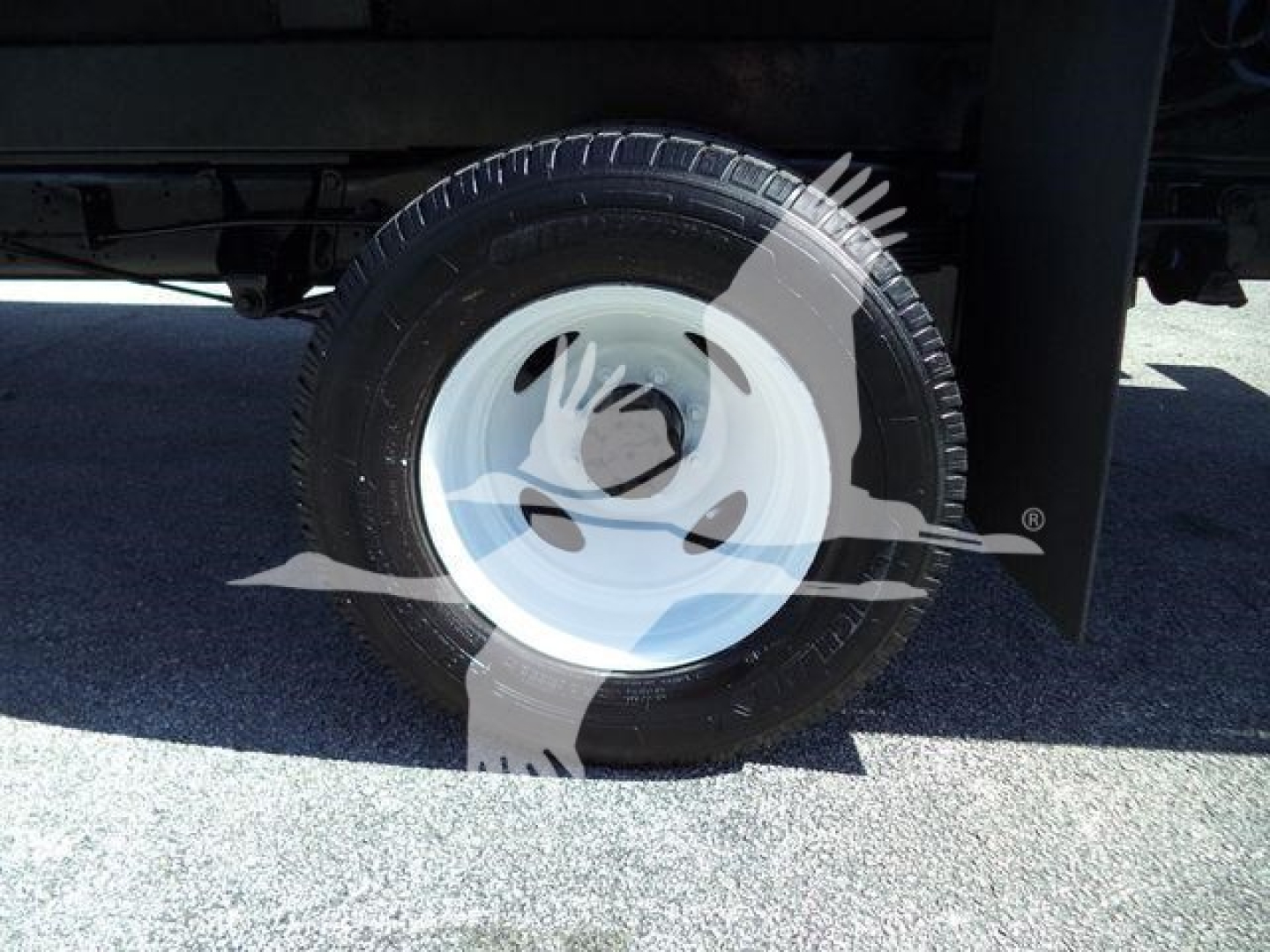 Ford E450 flatbed truck wheel and tire visible under chassis, white steel rim with black tire.