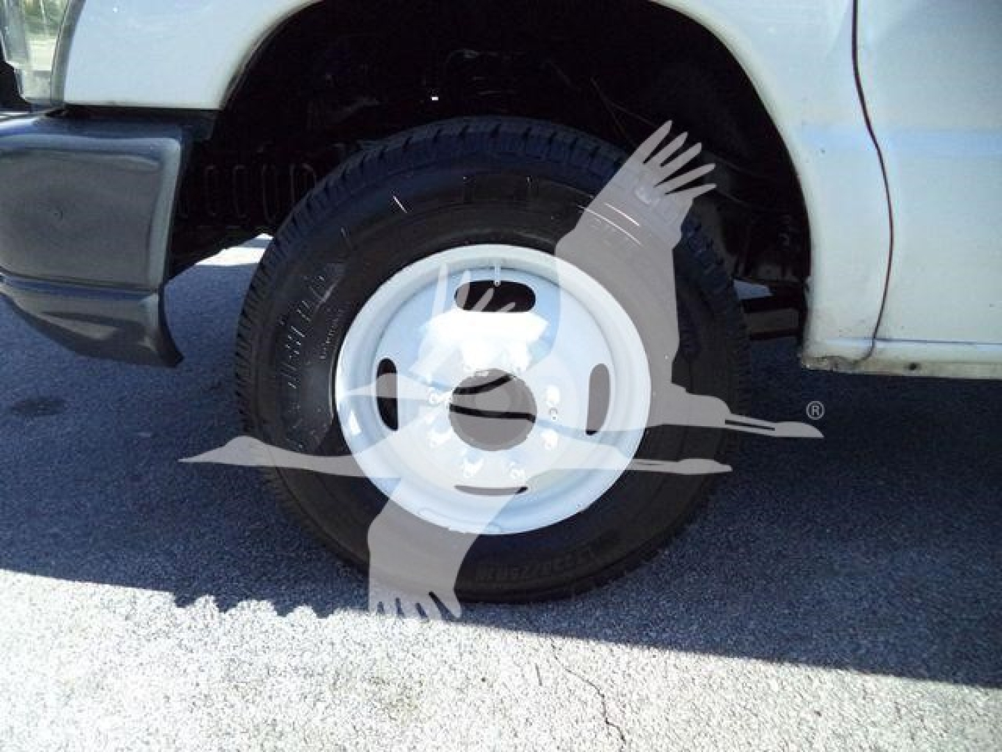 Ford E-450 front wheel and fender view showing steel wheel with black tire and white hubcap.