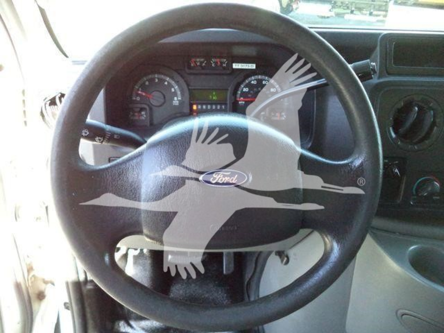 Ford E-Series van interior showing steering wheel, dashboard gauges, and steering column view.